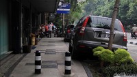 Tampak beberapa mobil parkir hingga naik ke trotoar jalan. 
