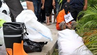 Para pelaku melakukan rekonstruksi dengan memakai penutup kepala. Tangan mereka juga diborgol.