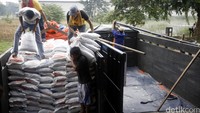 Pekerja menata karung-karung beras yang akan didistribusikan.