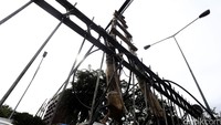 Tangga kayu yang digunakan untuk menyangga kabel diikatkan ke pagar pembatas. Tangga itu diikat agar tidak ambruk.