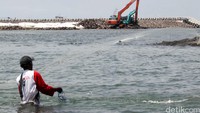 Seorang nelayan menjala ikan di sekitar proyek reklamasi.