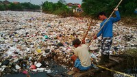 Sejumlah warga berjibaku menyingkirkan sampah-sampah agar air sungai kembali lancar.