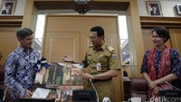 Kepala Sekolah JIS Tim Carr memberikan cinderamata kepada Gubernur DKI Jakarta Basuki Tjahaja Purnama berupa lukisan.