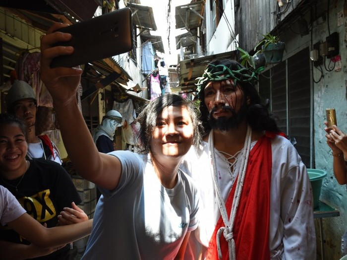 A spectator takes a selfie with an actor playing the role of Jesus during the reenactment of the suffering and crucifixion of Jesus in a street play as part of Lenten observance during Holy Week in Manila on March 24, 2016, ahead of Easter. 
Christian believers around the world mark the Holy Week of Easter in celebration of the crucifixion and resurrection of Jesus Christ. / AFP / TED ALJIBE