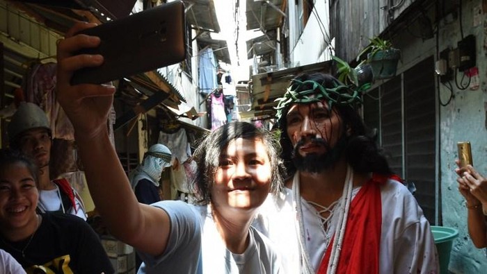 A spectator takes a selfie with an actor playing the role of Jesus during the reenactment of the suffering and crucifixion of Jesus in a street play as part of Lenten observance during Holy Week in Manila on March 24, 2016, ahead of Easter. 
Christian believers around the world mark the Holy Week of Easter in celebration of the crucifixion and resurrection of Jesus Christ. / AFP / TED ALJIBE
