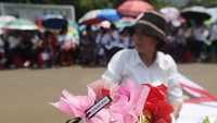 Mereka memakai payung dan membawa karangan bunga.
