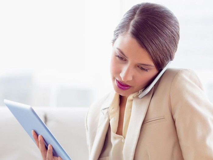 Busy businesswoman sitting on sofa multi tasking