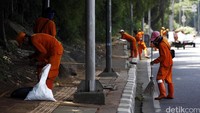 Pasukan oranye membersihkan sampah di Jalan Gatot Subroto, Jakarta.