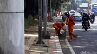 Dua orang petugas menyapu sampah di Jalan Gatot Subroto, Jakarta.