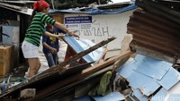 Warga membereskan papan-papan rumah mereka yang dibongkar.
