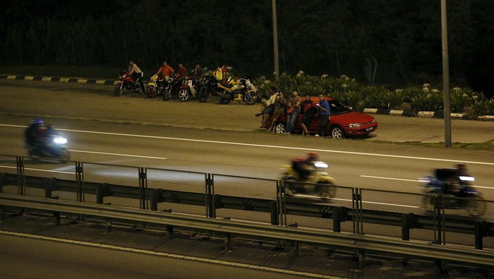 Spectators watch motorbike racing on a highway in Kuala Lumpur, Malaysia, April 19, 2015. Crowds of small motorbikes ridden by racers - or 