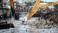 Sejumlah alat berat membersihkan puing-puing sisa gusuran di dalam sungai.