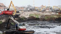 Alat berat mengeruk lumpur dari dasar sungai.