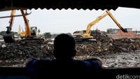 Dua alat berat membersihkan puing-puing bangunan dari dalam sungai.