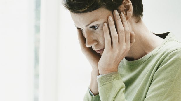 Anxious Woman Sits at a Desk Using a Laptop and Paying a Bill Online