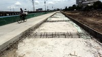 Pengendara sepeda melintas di jalan yang masih dalam tahap pembangunan.