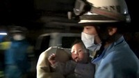 Petugas penyelamat menyelimuti bayi ini dan bergegas membawanya ke ambulans. Reuters/Kumamoto Prefectural Police/Handout via Reuters.