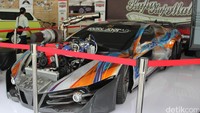 Bengkel modifikasi langganan juara kontes modifikasi Kupu-kupu malam kembali memperlihatkan kehandalan mereka. Mobil garapan mereka terlihat sangat panjang, dengan mesin besar yang dibiarkan terekspos di bagian atas kap mesin. Roda mobil pun mirip roda truk, 6 buah. Foto: Dadan Kuswaraharja