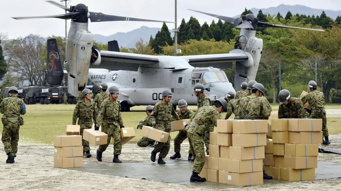 Japan Ground Self-Defense Force soldiers carry aid materials from a U.S. military Osprey aircraft (behind them) after a series of earthquakes, at Hakusui sports park in Minamiaso town, Kumamoto prefecture, southern Japan, in this photo taken by Kyodo April 18, 2016. Mandatory credit REUTERS/Kyodo  ATTENTION EDITORS - FOR EDITORIAL USE ONLY. NOT FOR SALE FOR MARKETING OR ADVERTISING CAMPAIGNS. THIS IMAGE HAS BEEN SUPPLIED BY A THIRD PARTY. IT IS DISTRIBUTED, EXACTLY AS RECEIVED BY REUTERS, AS A SERVICE TO CLIENTS. MANDATORY CREDIT. JAPAN OUT. NO COMMERCIAL OR EDITORIAL SALES IN JAPAN.