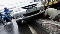 Honda City yang tersangkut pembatas jalan itu bernomor polisi B 1916 EEP.