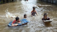 Anak-anak bermain di tengah banjir.