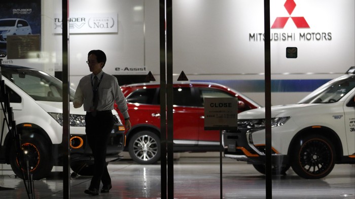 TOKYO, JAPAN - APRIL 20:  An employee  walks past a Mitsubishi Motors vehicles displayed at the companys headquarters on April 20, 2016 in Tokyo, Japan. Mitsubishi Motors share plunged more than 15% after the Japanese car maker announced it has mishandled the fuel economy test data.  (Photo by Tomohiro Ohsumi/Getty Images)