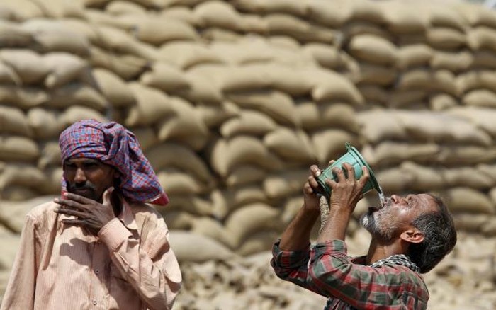 A labourer drinks water as another looks on, on a hot summer day at a grain market in Chandigarh, India April 19, 2016.