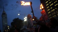 Dalam aksinya meraka tampak membawa obor dan poster bergambar wajah para mahasiswa yang menghilang. Edgard Garrido/Reuters