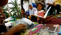 Beberapa anak membaca buku di perpustakaan keliling.