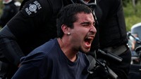 Seorang demonstran tampak diamankan petugas kepolisian setempat. David Ryder/Reuters/detikFoto.