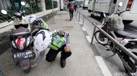 Petugas Kepolisian dari Lalulintas Polda Metro Jaya melakukan razia dengan mencabut pentil kendaraan sepeda motor yang diparkir diatas trotoar di Kawasan Jalan Sudirman, Jakarta Selatan, Senin (2/5/2016).