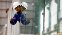 Seorang pekerja tengah memasang kaca di Garbarata pesawat.