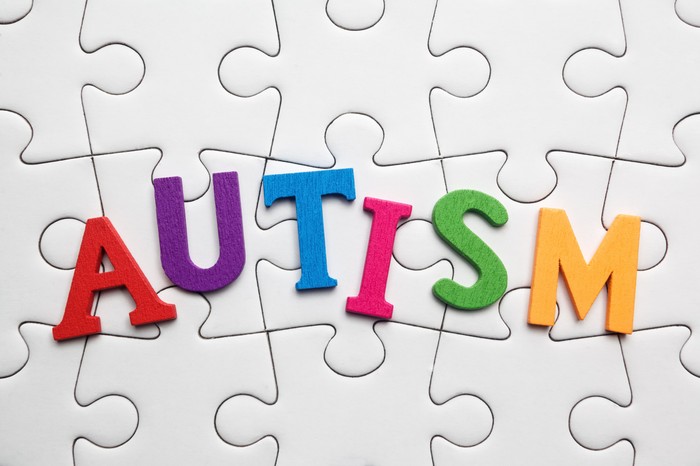 Word Autism built of wooden puzzles on a wooden background.