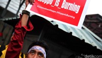 Pendemo mengusung poster Aleppo is Burning. Aleppo merupakan salah satu kota yang hancur akibat konflik Suriah.