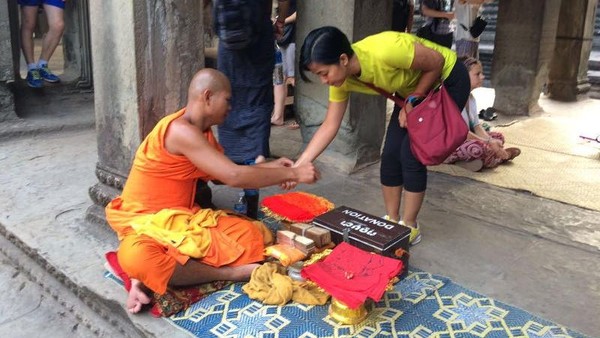 Foto: Beberapa biarawan terlihat di dalam Angkor Wat. Mereka memakai pakaian khas dan didekatnya ada kotak donasi. Saat kita memberikan donasi sejumlah uang, mereka akan memberikan gelang dan mengucapkan doa (Rangga/detikTravel)