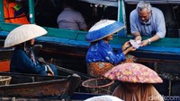 Para pedagang mengantre untuk menukarkan uang di kas terapung.