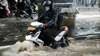 Pengendara sepeda motor nekat menerobos genangan.
