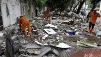 Pasukan orange membersihkan puing-puing bekas tanaman hias dan ornamen taman di trotoar Jalan Asia Afrika, Senayan.