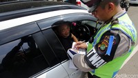 Polisi menilang pengendara yang melanggar lalu lintas.