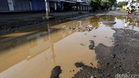 Usai diguyur air hujan, jalanan tersebut tampak dipenuhi kubangan air.
