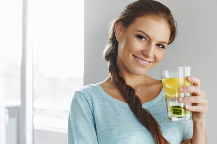 Healthy Lifestyle, Food. Happy Woman Drinking Summer Refreshing Fruit Flavored Infused Water With Fresh Organic Lemon, Lime, Mint. Detox Vitamin-fortified Water. Healthy Eating. Vitamin, Diet Concept.