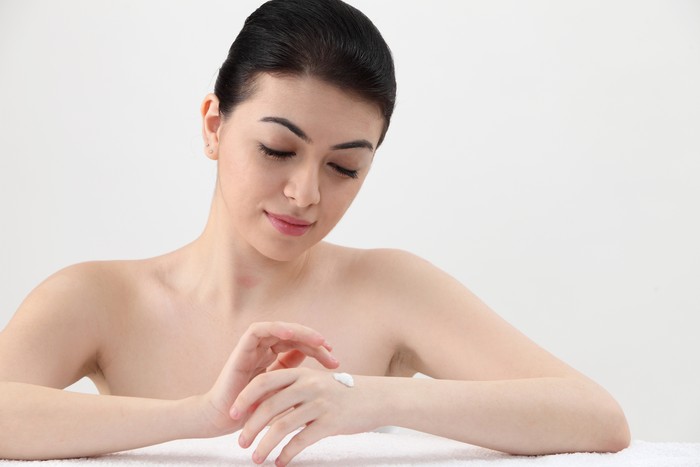 Ilustrasi Beauty Young beautiful girl applying lotion with eyes closed