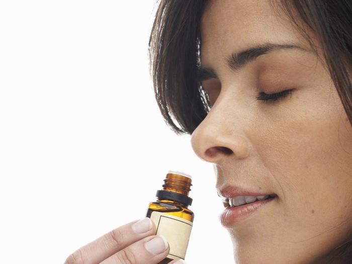 Young woman smelling aromatherapy oil, eyes closed