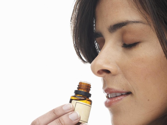 beautyingredients-0009 Young woman smelling aromatherapy oil, eyes closed