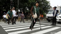 Beberapa penyandang disabilitas menyeberang jalan untuk menghadiri peresmian Portal S di RSCM.