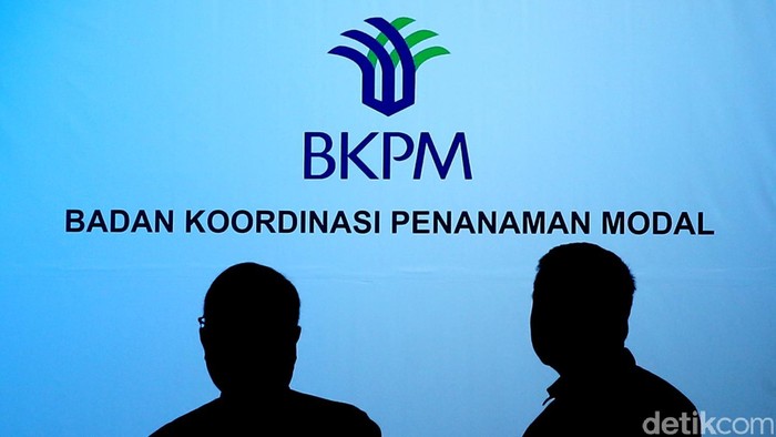 Siluet pegawai dan tamu di depan logo Badan Koordinasi Penanaman Modal (BKPM)