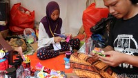 Ozza dan Icha merampungkan kerajinan miniatur Ondel-ondel yang terbuat dari botol bekas air mineral.