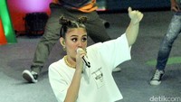 Agnez MO tampil dengan kaus putih Moschino, hot pants print penuh warna dan boots hitam selutut. Pool/Noel/detikFoto.