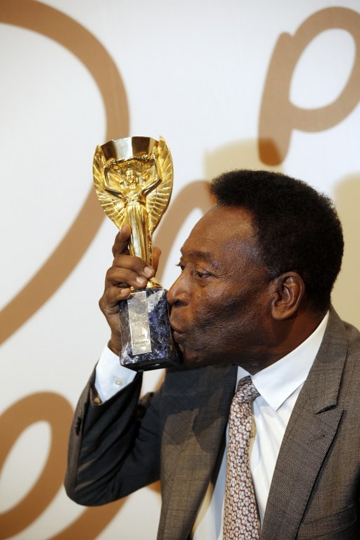 Pele dan jules Rimet Former Brazilian footballer Pele kisses a replica Jules Rimet trophy, a trophy awarded to the winner of the football World Cup, during an media interview at a preview for an auction of his memorabilia in London on June 1, 2016.
The three-time World Cup winner and FIFA Player of the Century is offering to auction his vast memorabilia collection including awards, personal property and iconic items from his entire career. The collection is being offered by Julien's Auction House on June 7, 8, 9 in London. / AFP PHOTO / ADRIAN DENNIS