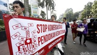 Demonstran membentangkan spanduk di depan Kemenristekdikti.